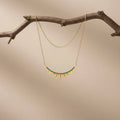 A graceful layered necklace featuring fine chains and subtle pendant details. Its minimalist design makes it perfect for everyday elegance and effortless with green layering.